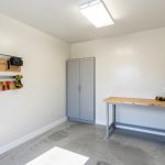 Intérieur de garage rénové et bien isolé, murs clairs, outils rangés et ambiance chantier propre et lumineuse.