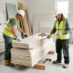 Chantier de rénovation professionnel organisé, avec une équipe équipée de protections de sécurité travaillant parmi des matériaux et outils soigneusement rangés.